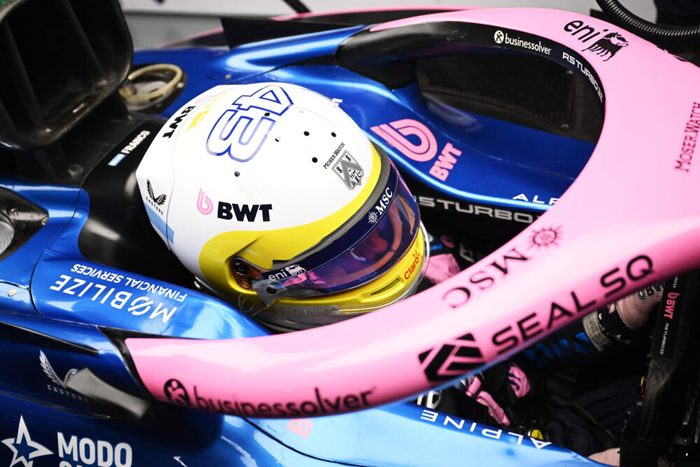 A close-up overhead view of a Formula 1 driver wearing a helmet inside an Alpine F1 Team car. 