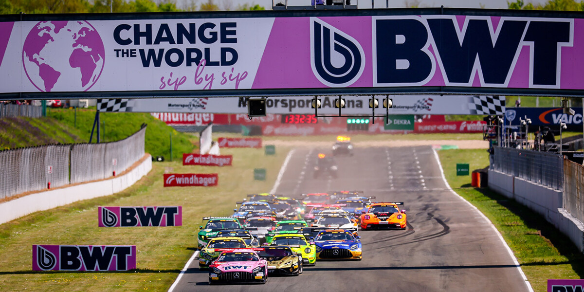 A thrilling group of race cars accelerate down the track, framed by prominent BWT branding and a banner promoting 'Change the World sip by sip.' 