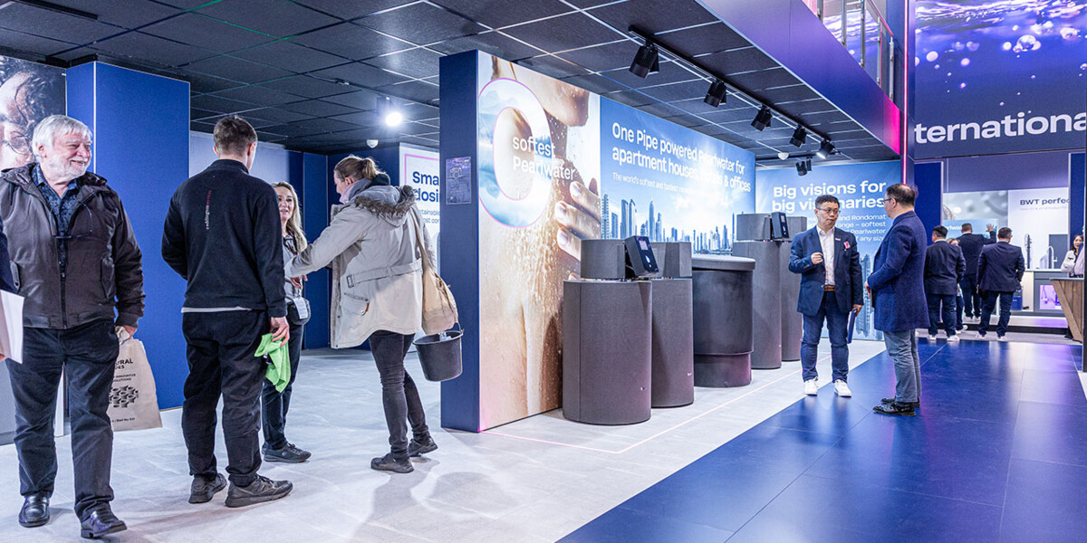 A vibrant BWT exhibition booth at a trade show captures attendees engaging with modern water filtration displays and interactive presentations. 