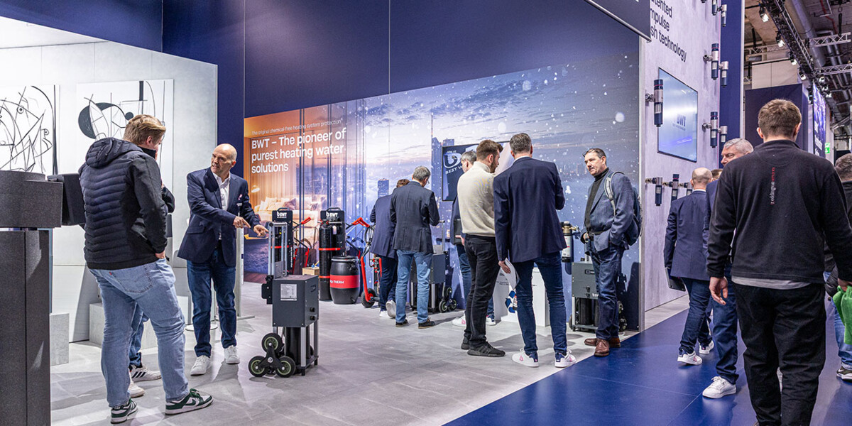 Professionals gather at a modern exhibition booth featuring BWT water treatment solutions.