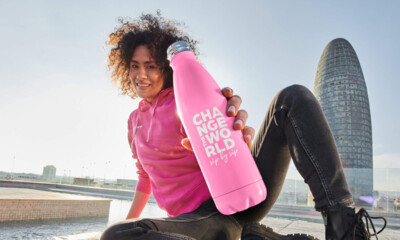 A woman with a pink BWT water bottle on a square in front of a skyscraper. 