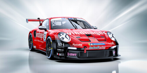 A dynamic, front-angle view of a red Porsche 911 GT3 race car featuring a Windhager logo and aerodynamic detailing. 
