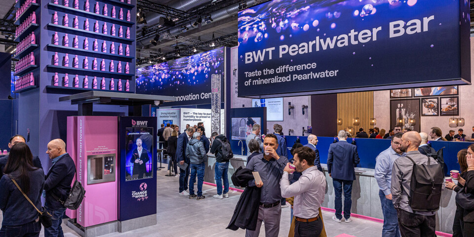 Visitors gather at the BWT Pearlwater Bar, where a large sign invites attendees to taste mineralized Pearlwater. 